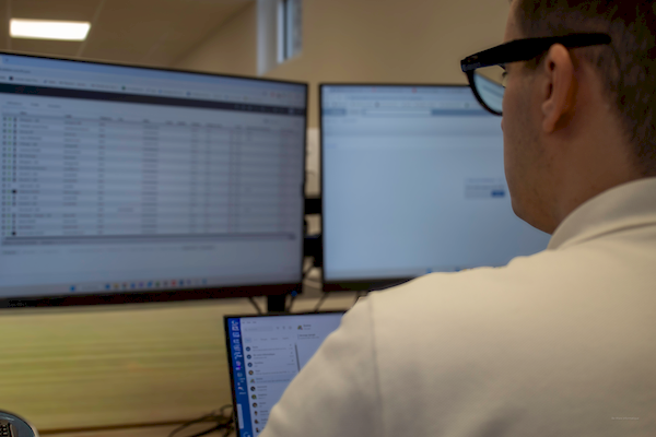 Technicien contrôlant la sécurité et l'état du parc informatique client sur écrans de supervision