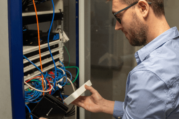 Technicien en baie informatique évaluant la solution internet idéale entre fibre optique et borne 4G
