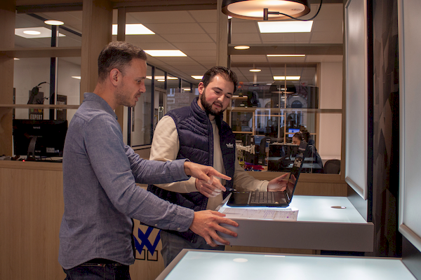 Technicien informatique échangeant avec un client lors de la remise de son poste de travail