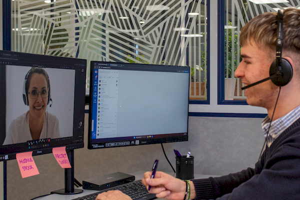 Collaborateur en visioconférence client utilisant messagerie interne instantanée et planning partagé sur ses écrans